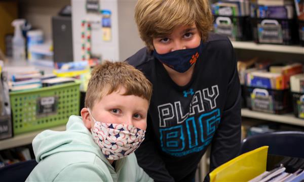 Two boys smile while wearing masks